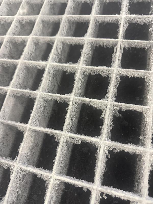 A booth grate caked in white overspray buildup